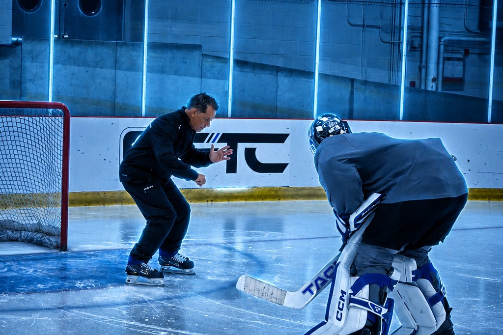 A coach working with a goaltender on the ice during an FTC session